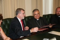 El rector y el obispo intercambian ejemplares del convenio firmado